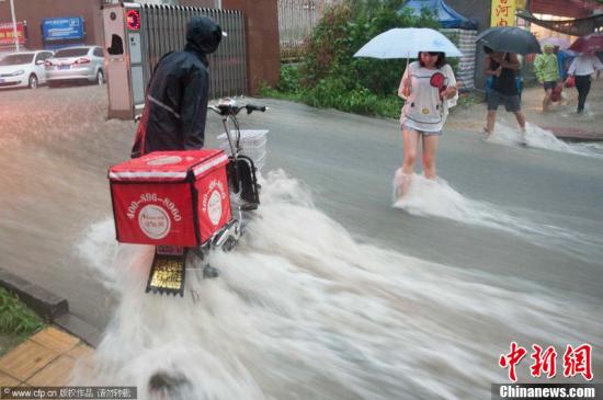 2012年7月21日，北京普降暴雨，朝陽區北部立水橋南地區積水嚴重。一小區門口，積水沿斜坡形成巨大水流，阻礙人們通行。圖片來源：CFP視覺中國